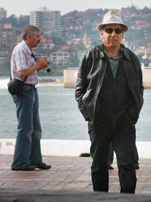 Paul walking around unnoticed, guy behind him doesn't know where the attraction is.