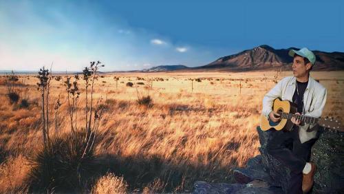Paul Simon in South Africa playing the guitar in the Savannah